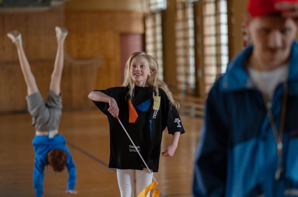 Children having fun in a school gym, with gymnastics and playful activities.