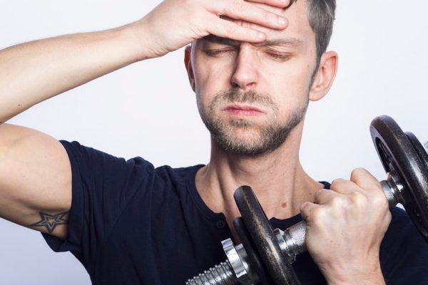 man in black crew neck t-shirt holding black dumbbell